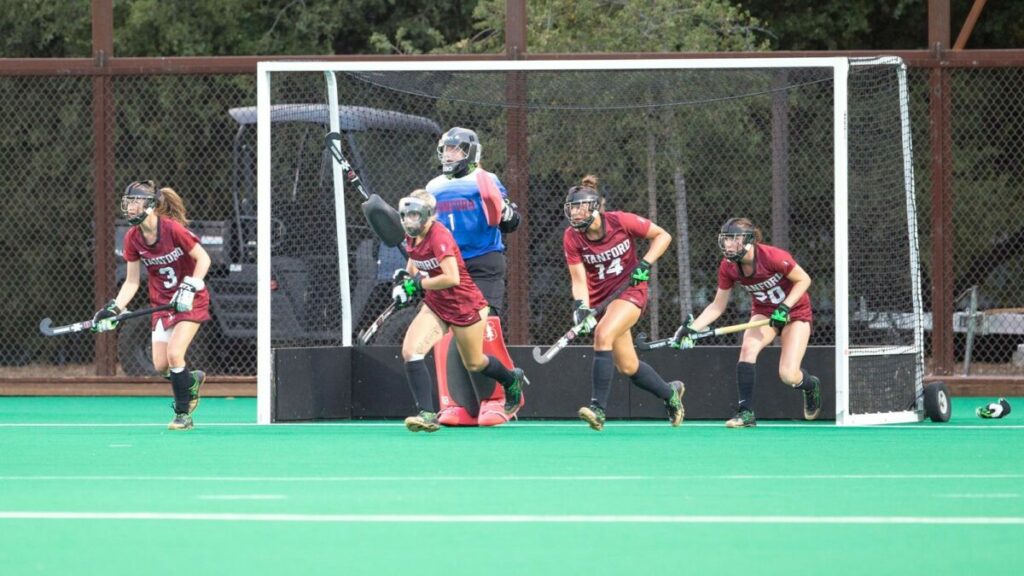 A team of women, including Defender Julia DiTosto, playing field hockey on a field.