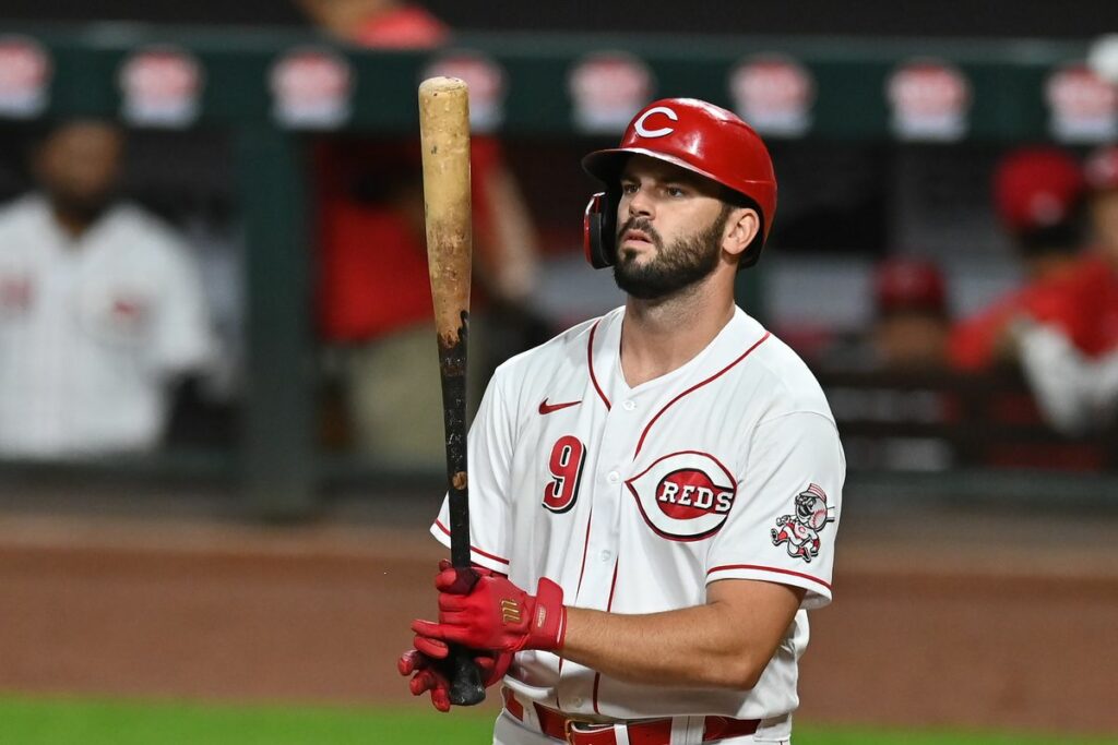 Mike Moustake is holding a bat in front of a crowd.